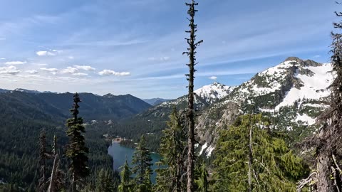 Alpine lake and snowy peaks viewed through mountain trees